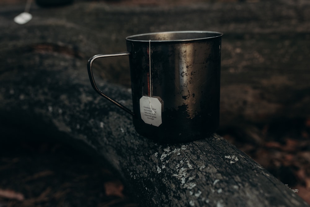 une tasse en métal posée sur une bûche