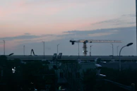 Evening shot of construction lights glowing softly against a darkening sky.