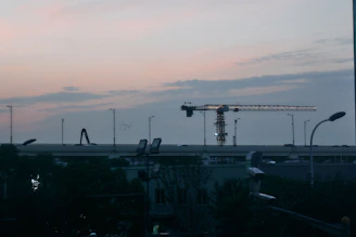 Evening shot of construction lights glowing softly against a darkening sky.