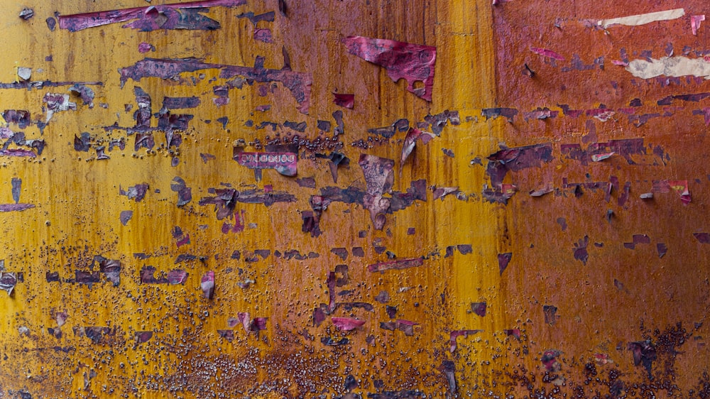 a yellow and red wall with peeling paint