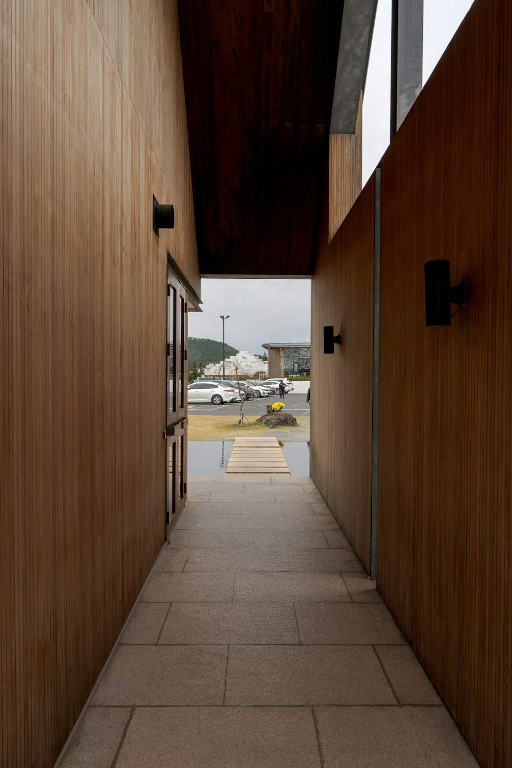 a long hallway with wooden walls leading to a parking lot