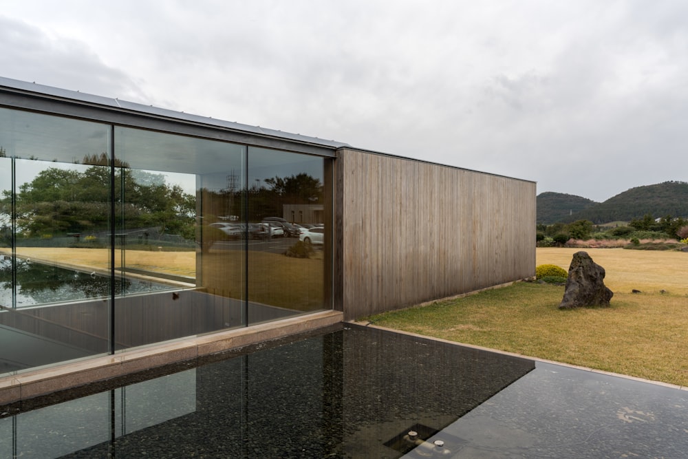 a house with glass walls and a large rock in front of it