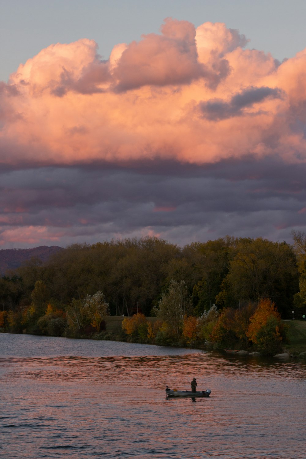 a person in a boat on a river under a cloudy sky