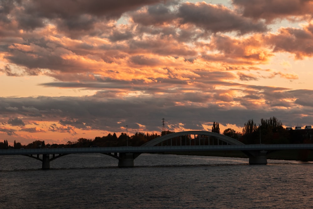 a bridge over a body of water under a cloudy sky