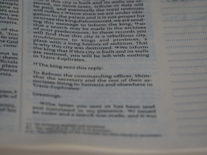 A close-up of a page from a book showing text in two columns. The text appears to be historical or biblical, indicated by the formal language and structure. The page includes a passage discussing a city's rebellious history and the response from a king.