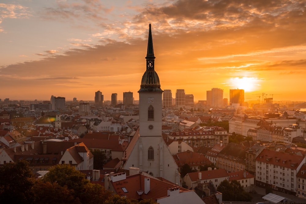 a sunset view of a city with a church steeple