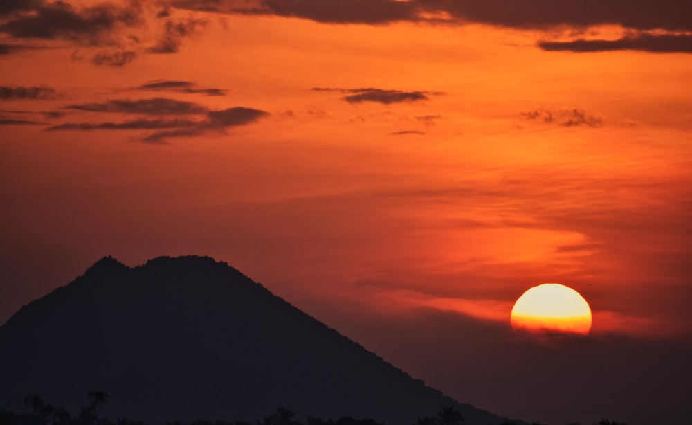 the sun is setting over a mountain in the distance