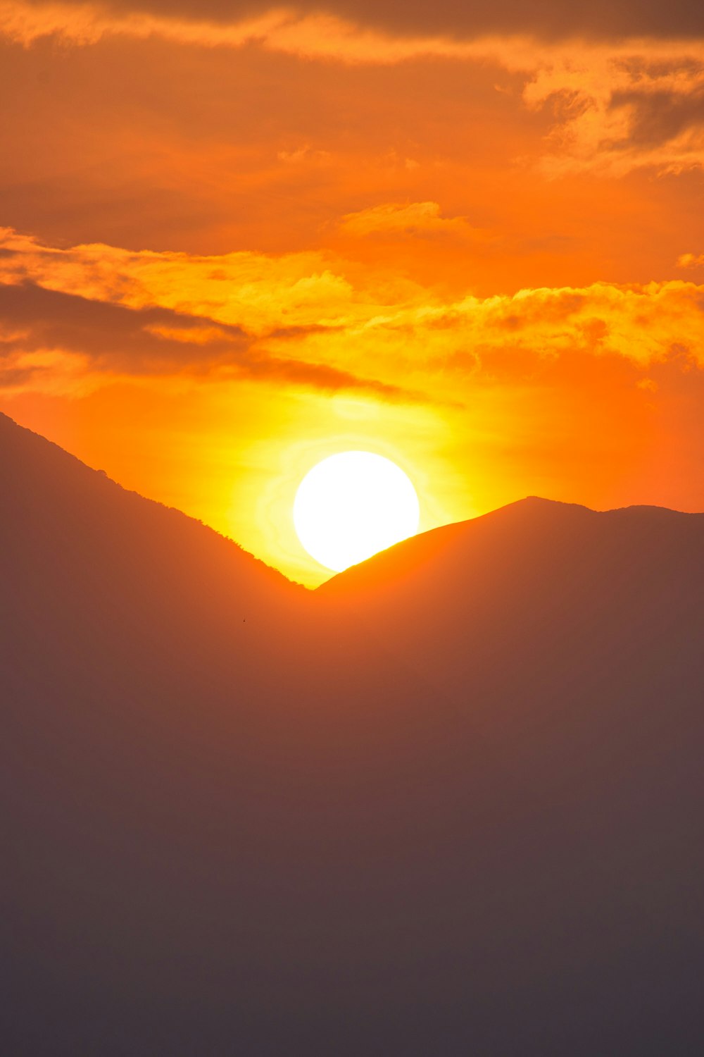 the sun is setting over a mountain range