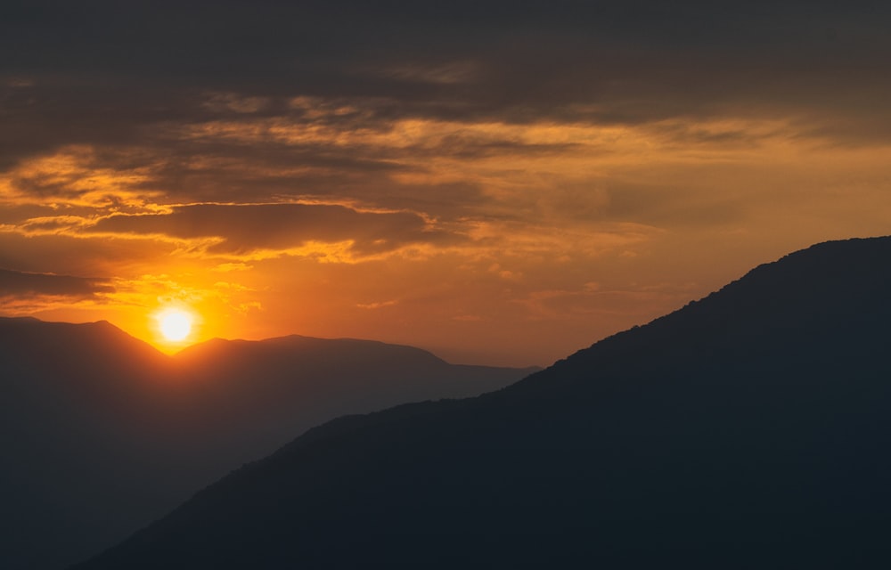 the sun is setting over a mountain range