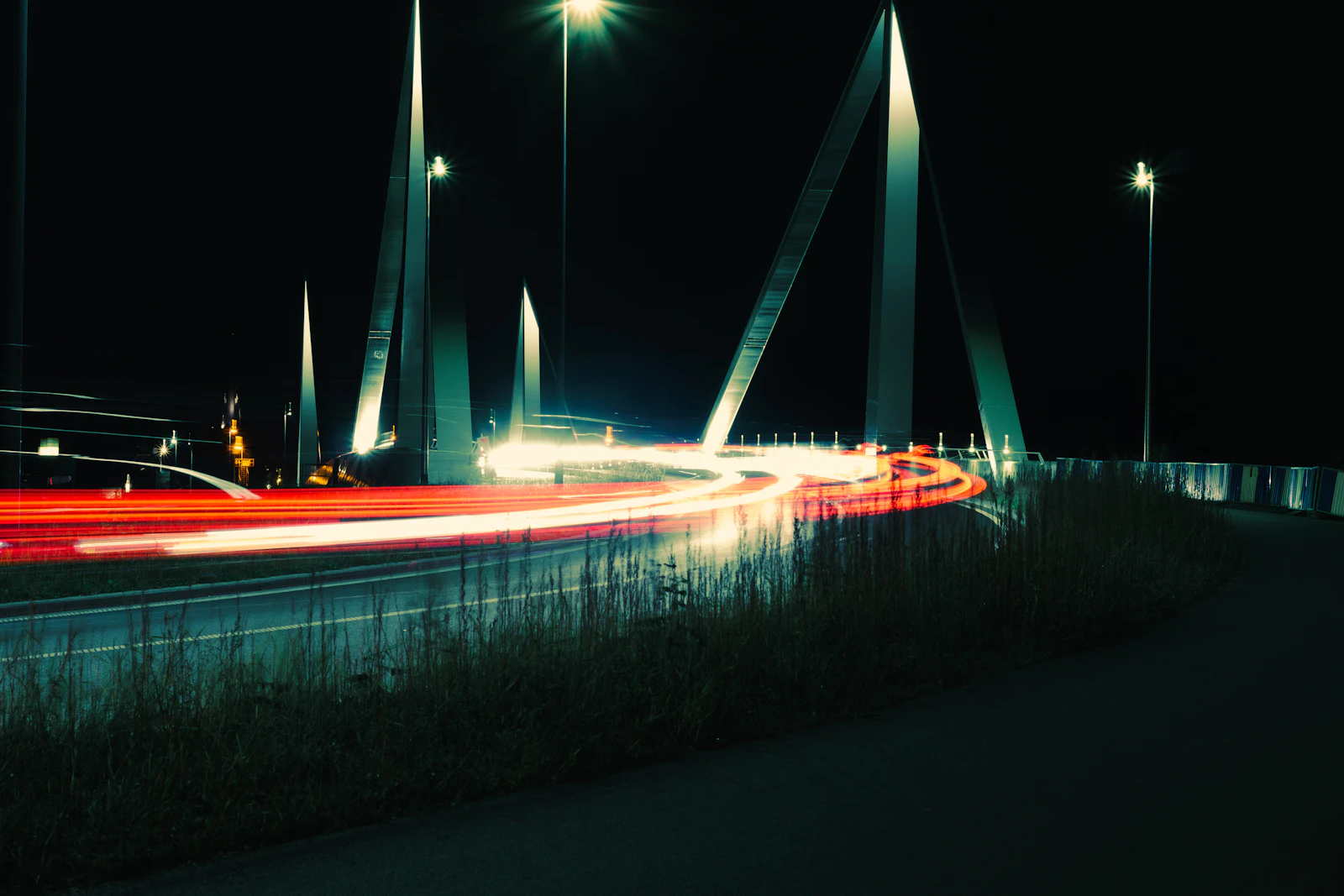 Long-exposure night view of an illuminated bridge with light trails from passing traffic