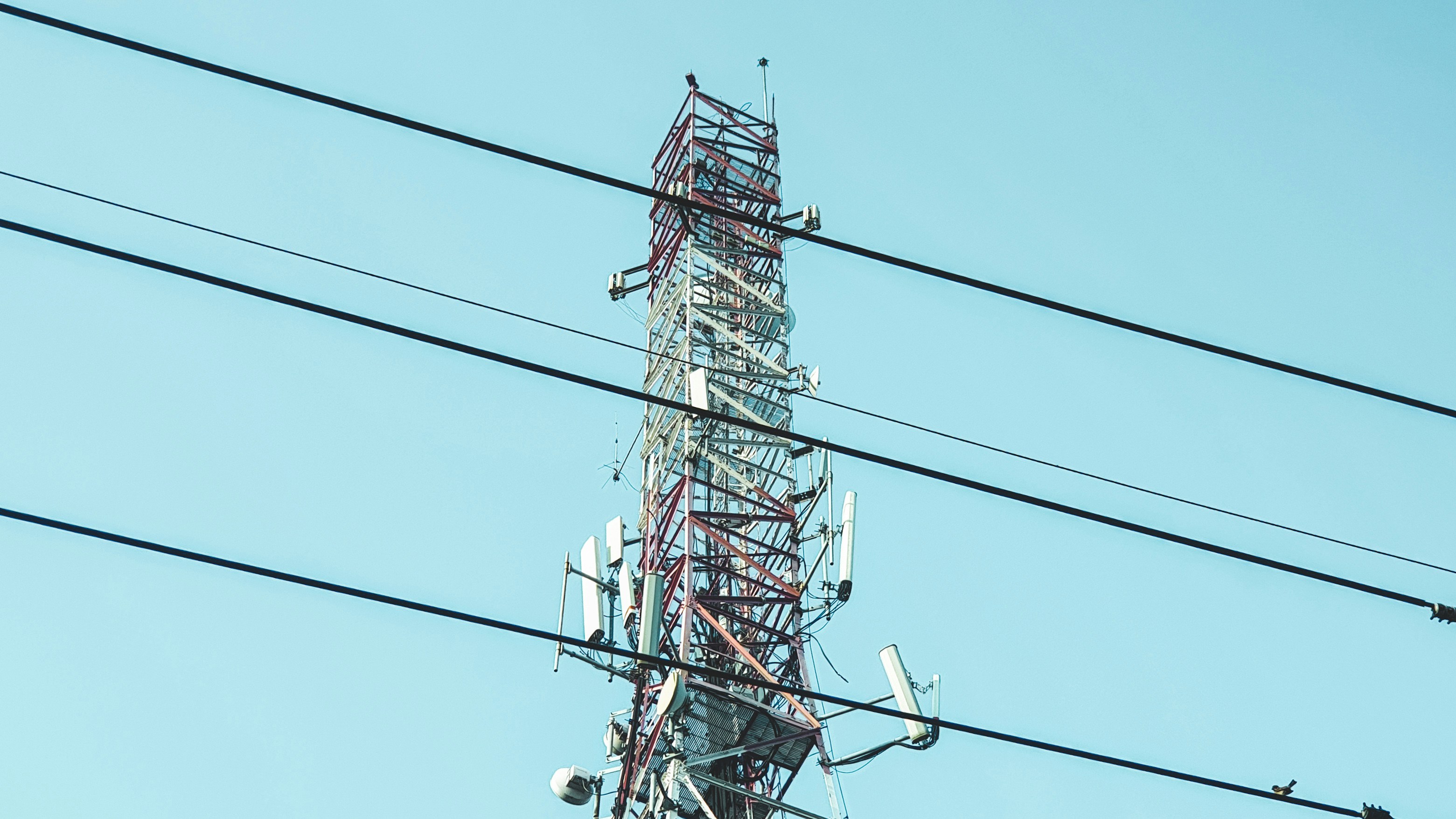 Cell tower and telecommunications antenna against a blue sky
