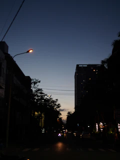 An urban street scene at dusk with glowing lights and lively shadows.