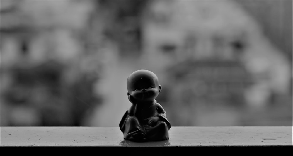 a black and white photo of a small buddha statue