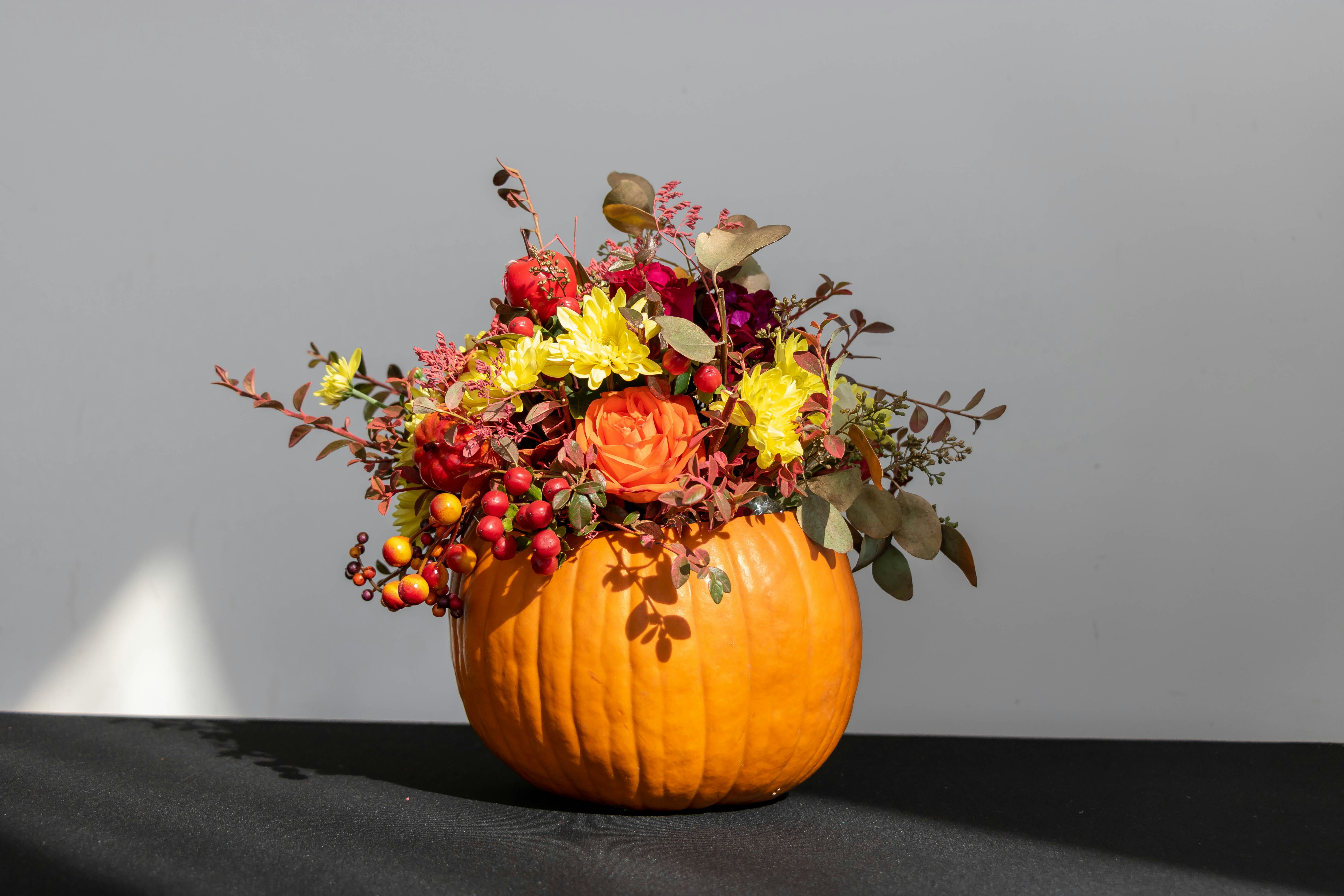 a pumpkin filled with lots of flowers on top of a table