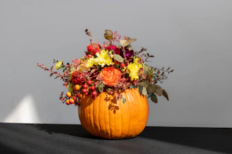 a pumpkin filled with lots of flowers on top of a table