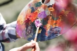 A close-up of a hand mixing vibrant paint colors on a palette.