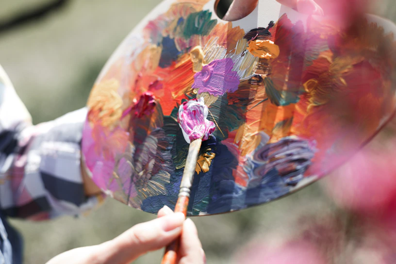 A vibrant close-up of a painter's hands mixing colors on a palette at the festival.