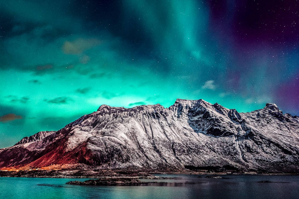 a mountain covered in snow under a green and purple sky