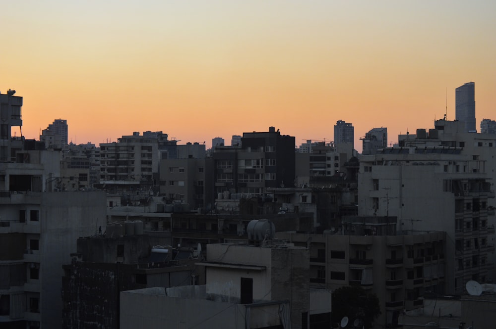 a city skyline at sunset with buildings in the foreground