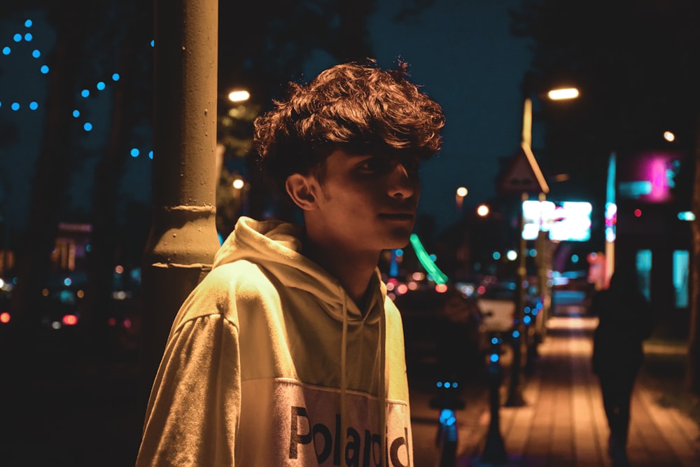 a young man standing on a sidewalk at night