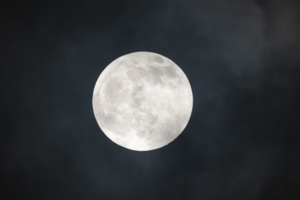 Una luna llena en un cielo oscuro con nubes