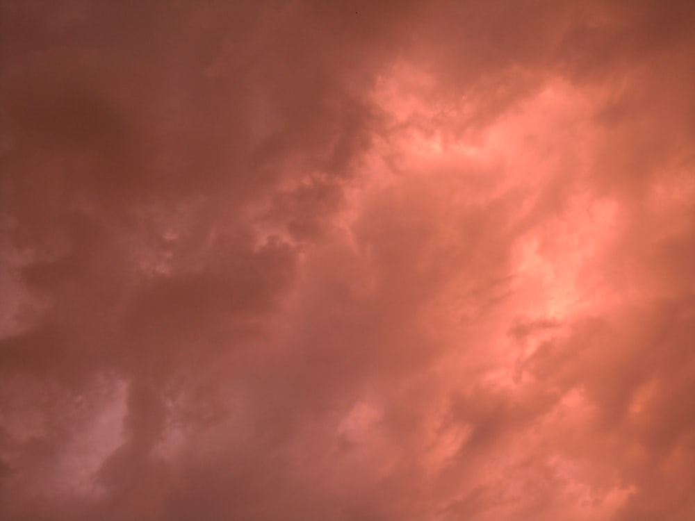 a plane flying in a cloudy sky at sunset