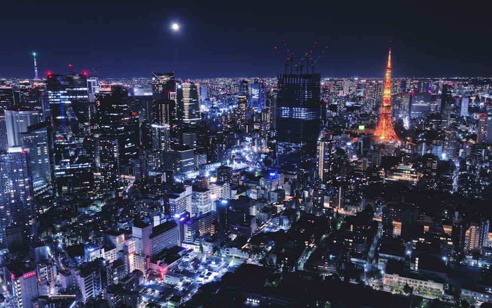 a view of a city at night with the moon in the sky