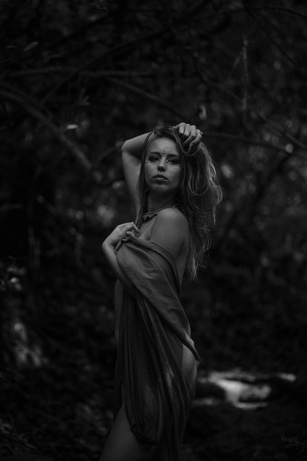 a woman with long hair standing in a forest