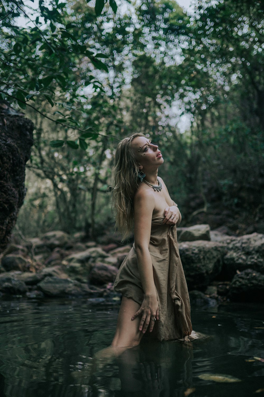 a woman standing in a river with trees in the background