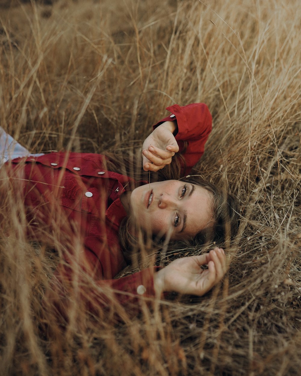 a woman laying in a field of tall grass