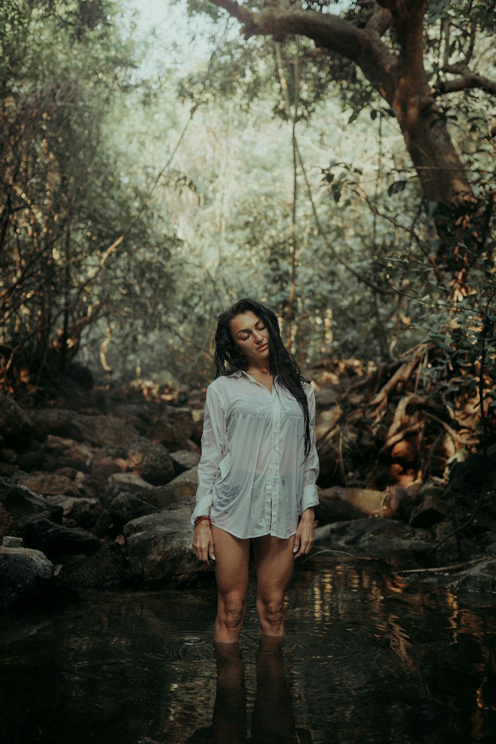 a woman standing in a stream in a forest
