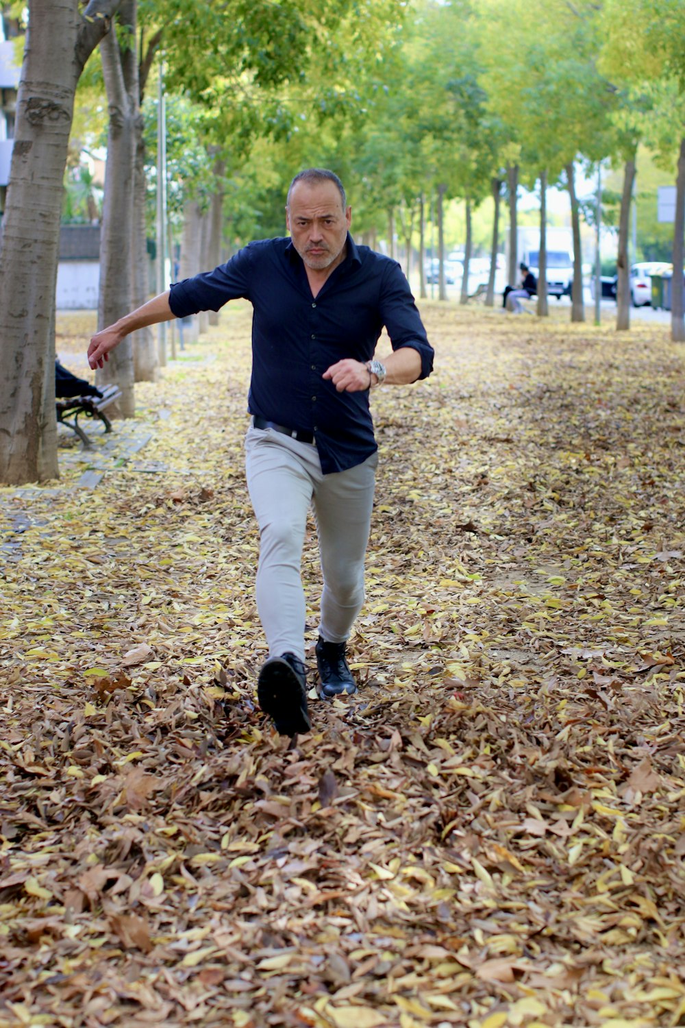 a man walking through a leaf covered park