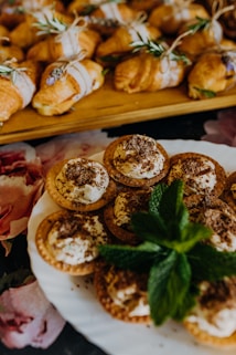 a white plate topped with pastries next to a tray of other pastries