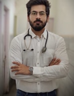 a man with a stethoscope standing with his arms crossed