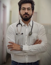 a man with a stethoscope standing with his arms crossed