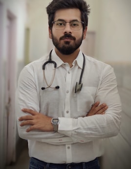 Photo of a friendly male orthopedic doctor with arms crossed in a hospital corridor