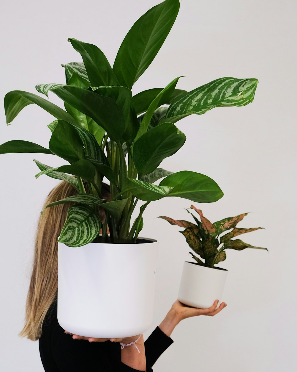 a woman holding two potted plants in front of her face