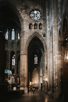 a person standing in a large cathedral with stained glass windows