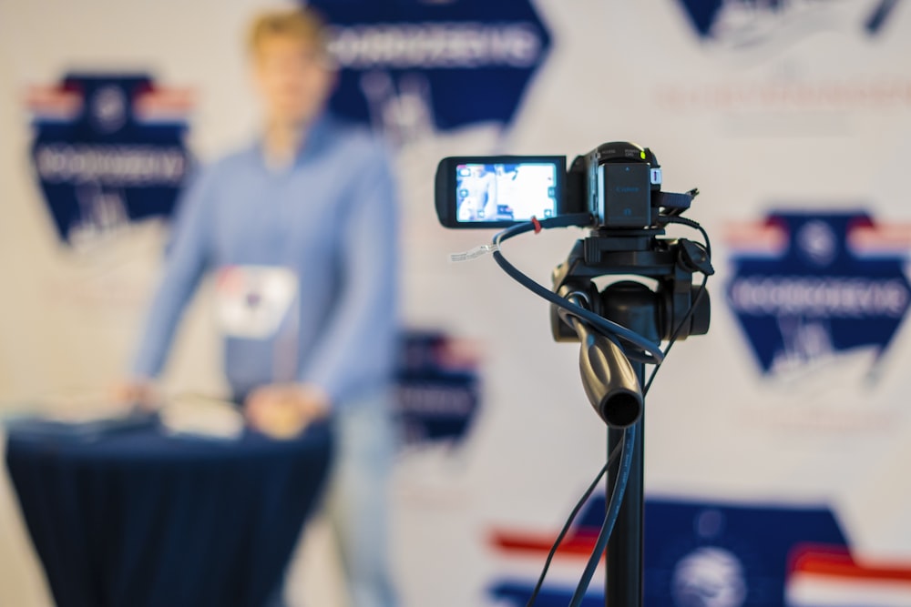 a person standing behind a microphone with a cell phone on a tripod