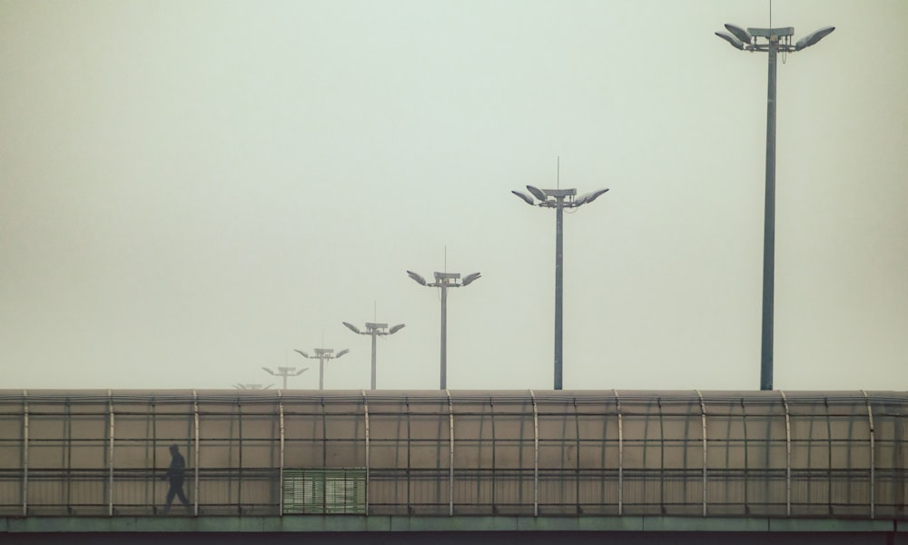 a person walking on a bridge next to a row of street lights