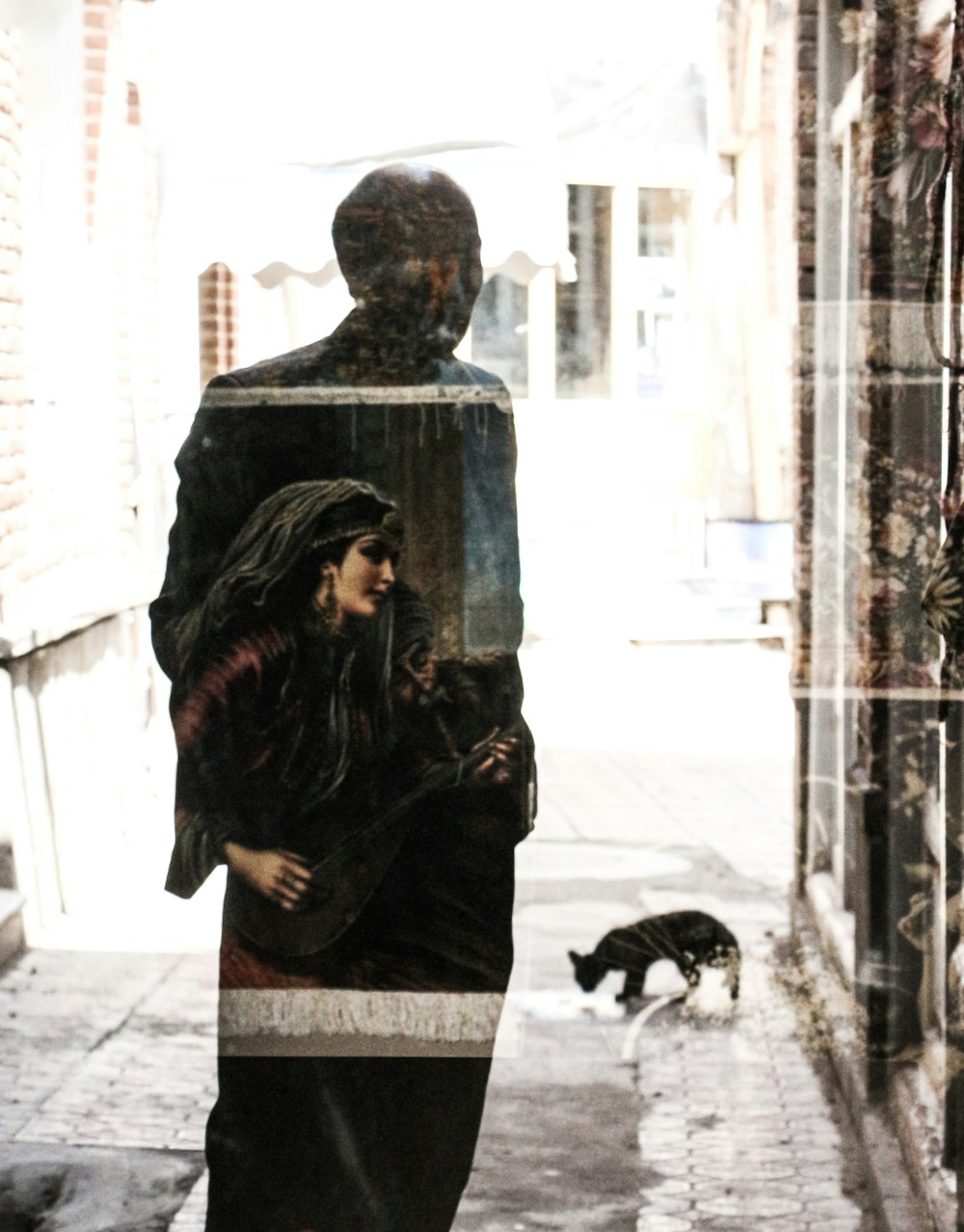 a woman walking down a street next to a cat