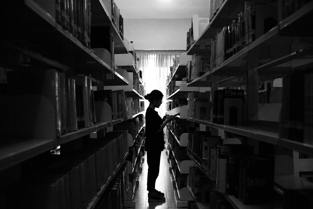 a person standing in a library with shelves full of books