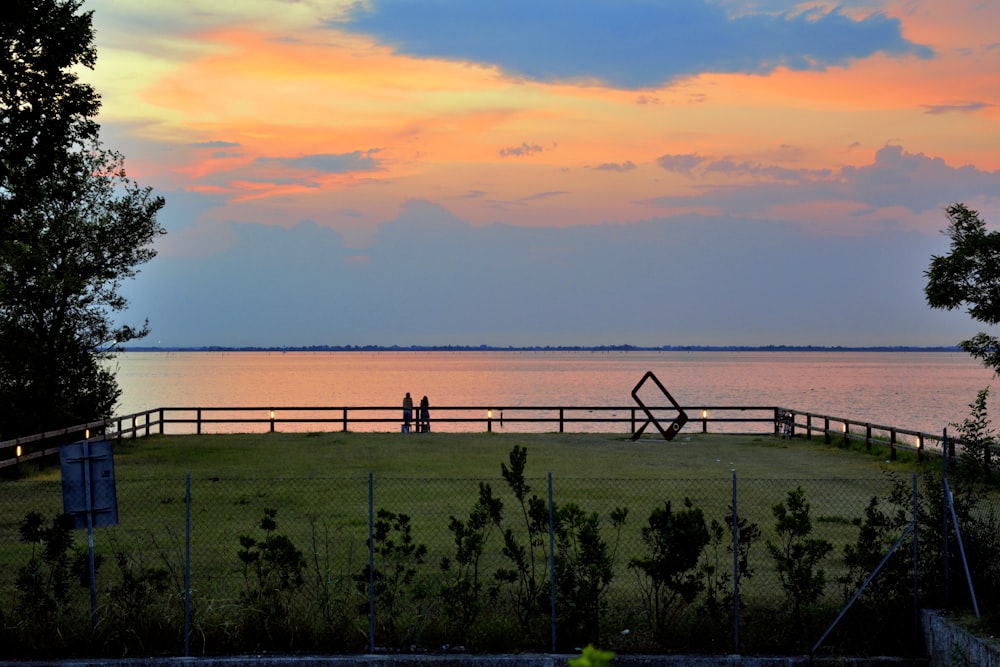 a couple of people sitting on a bench in front of a body of water