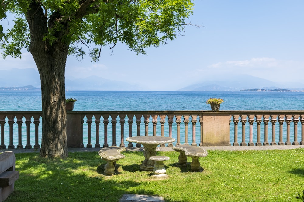 a bench and table in the grass by the water