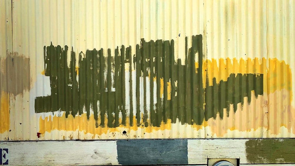 a rusted metal wall with yellow and green paint