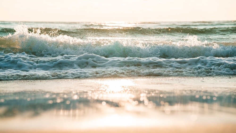 Le soleil brille sur l’eau alors que les vagues s’écrasent sur la plage