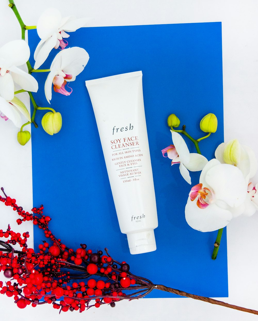 a tube of fresh soy face cream next to a bouquet of flowers