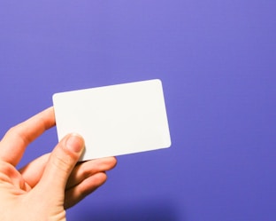 a hand holding a white business card against a purple background by Claire Abdo (@claireabdo)