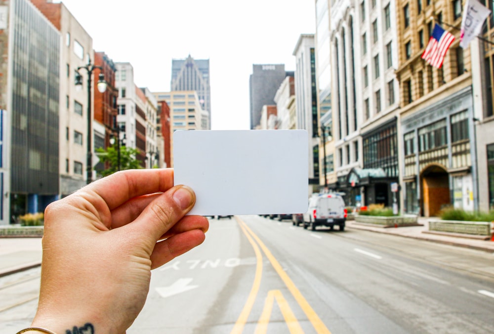 a person holding a business card in the middle of a street