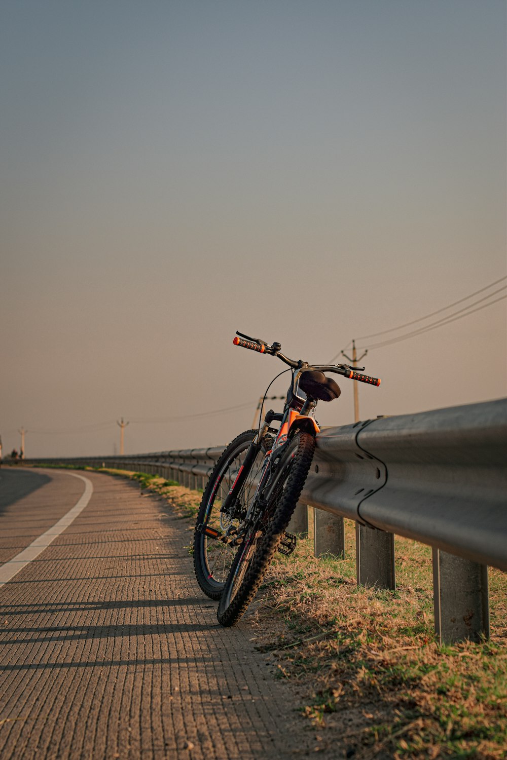 Una bicicleta apoyada contra una valla al costado de una carretera